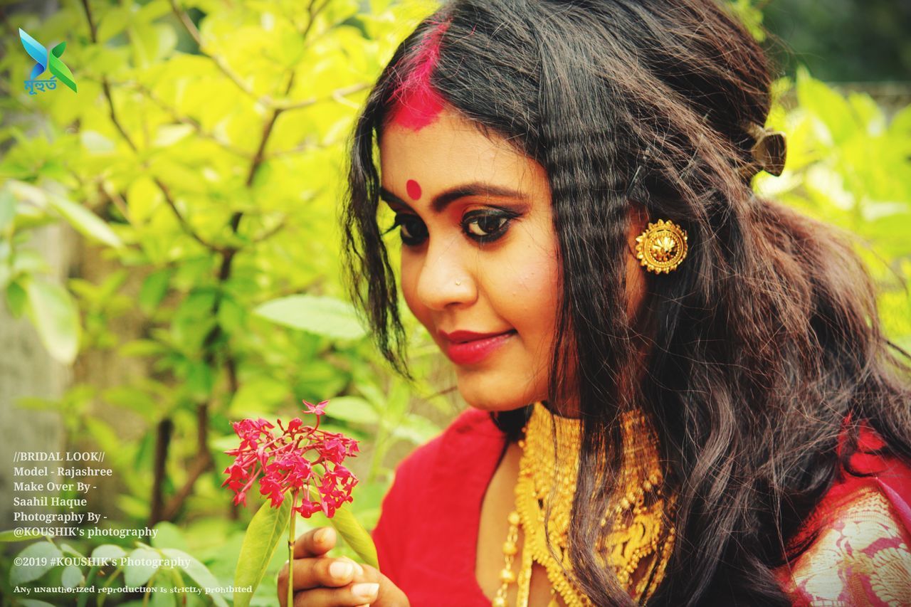 PORTRAIT OF BEAUTIFUL YOUNG WOMAN WITH RED FLOWER IN MOUTH