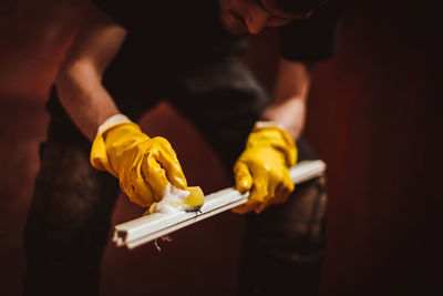 A young man washes window frames with water and a sponge.