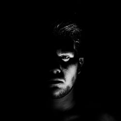 Close-up portrait of young man against black background