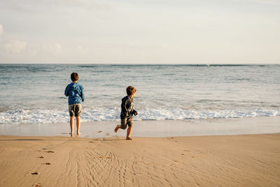 Carefree boys enjoying sea waves and sandy beach during weekend trip to sea
