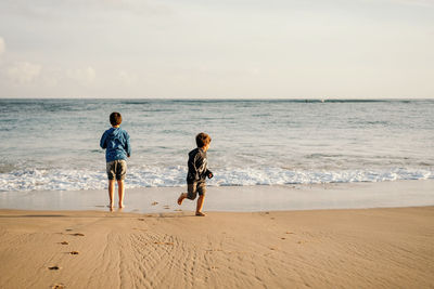 Full length of children on beach against sky