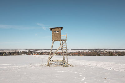 Raised hide on field against sky during winter