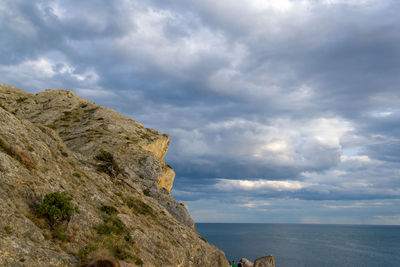 Scenic view of sea by cliff against sky