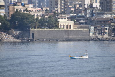 Sailboat sailing on river by buildings in city