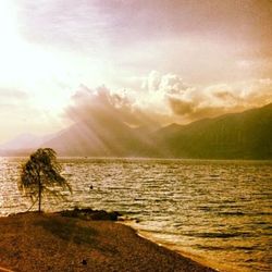 Sun shining through clouds over sea