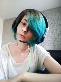 Low angle portrait of young woman listening music on headset at home