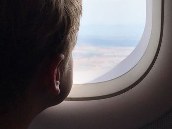 Close-up of man looking through airplane window