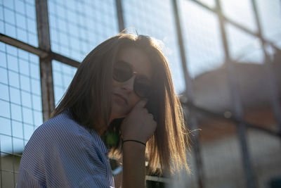 Portrait of young woman wearing sunglasses against metal grates