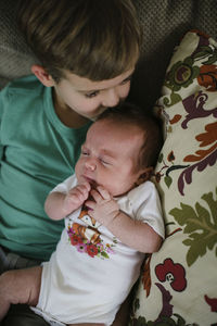 High angle view of brother kissing sister while lying on bed at home