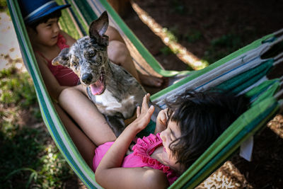 Two girls in hammock playing with the dog