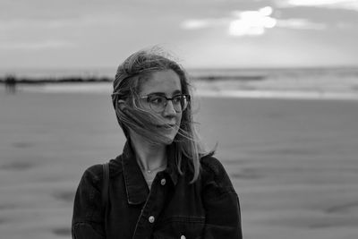 Portrait of woman standing at beach against sky