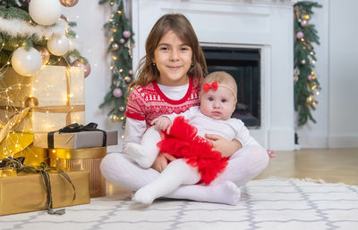 Portrait of girl with sister sitting on carpet at home