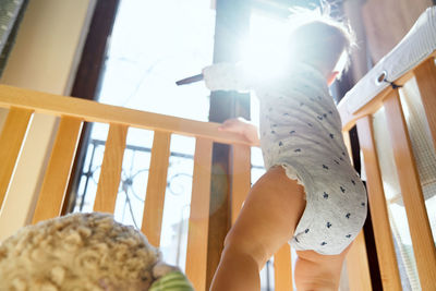 Low angle view of woman holding window at home