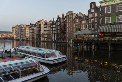 Boats in canal by buildings against sky in city