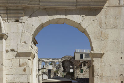 Buildings against sky seen through arch window