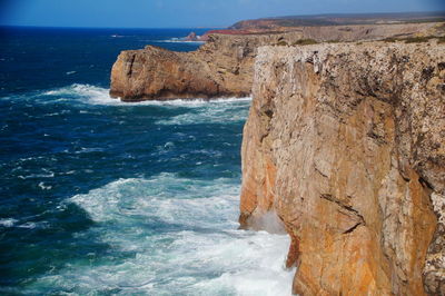 Rock formation on sea shore against sky