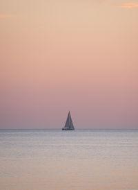 Sailboat sailing on sea against sky during sunset