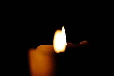 Close-up of lit candle in darkroom