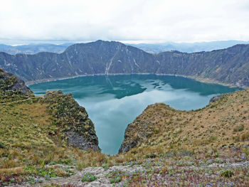 Scenic view of quilotoa volcanic crater lake and mountains against sky