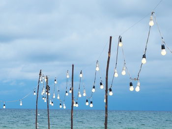 Wooden posts in sea against sky