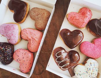 Directly above shot of colorful heart shaped donuts in boxes on table