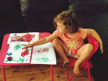High angle view of cute girl painting on paper