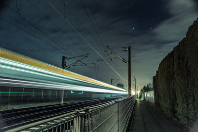 Light trails on railroad tracks against sky at night