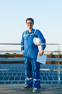 Portrait of young man standing against blue sky