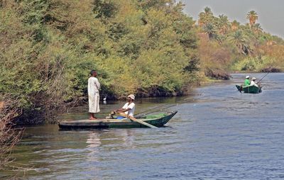 People in boat on river against trees