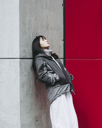 Woman in warm clothing leaning on wall