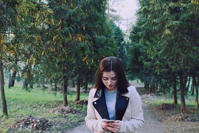Young woman using phone in forest