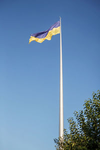 National flag of ukraine over clean blue sky background, kyiv city. pray for victory and freedom