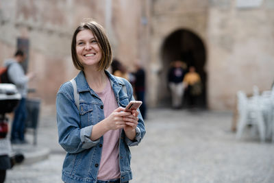 Smiling woman using smart phone in city