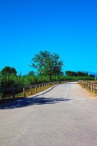 Empty road against clear blue sky