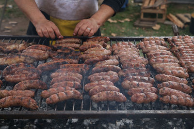 Midsection of man preparing meat on barbecue grill