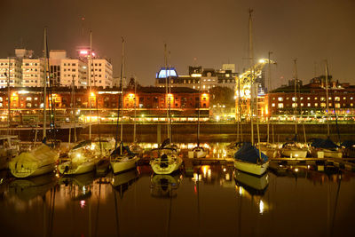 Boats moored in illuminated harbor at night