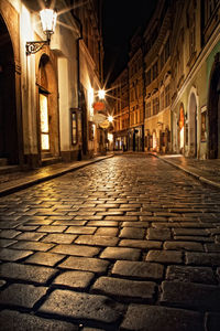 Footpath amidst illuminated buildings in city at night