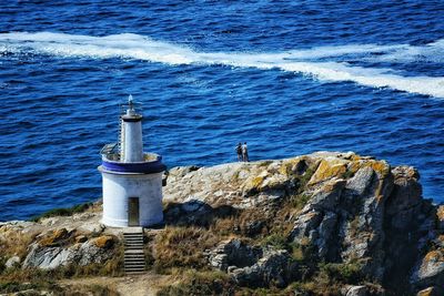 Lighthouse on shore against blue sky