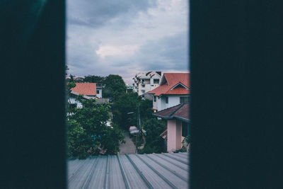 Houses by trees against sky