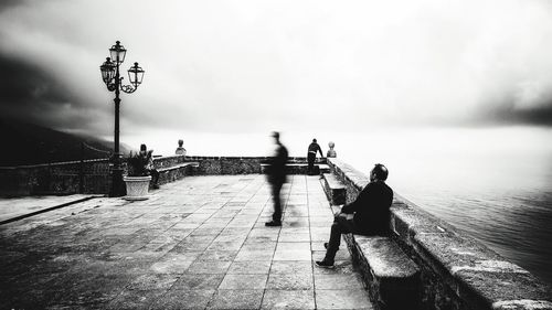 People on road by sea against sky