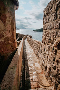 Footpath by sea against sky