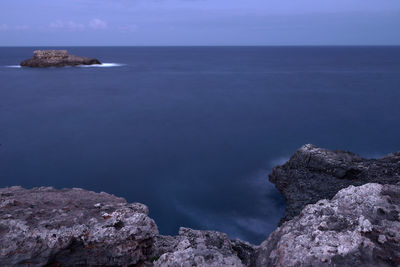 Scenic view of rock formation in sea against sky