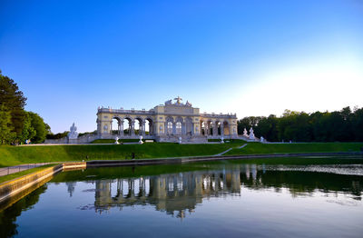 Reflection of building in water against clear blue sky