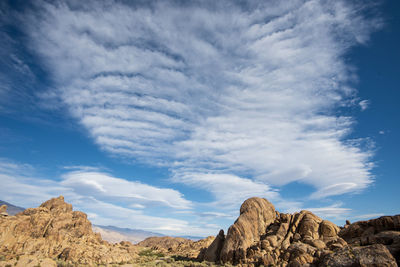 Rock formations in desert against clouds in blue sky