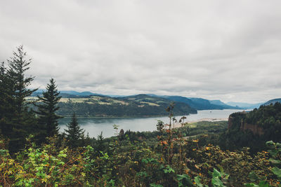 Scenic view of mountains and lake against cloudy sky