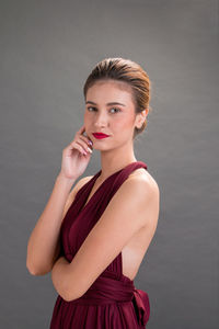 Portrait of beautiful young woman standing against gray background