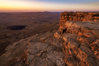 Rock formation on landscape against sky during sunset