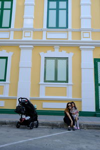 Full length of a man sitting against building