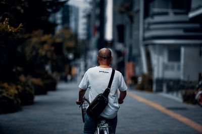 Rear view of man walking on street against buildings in city