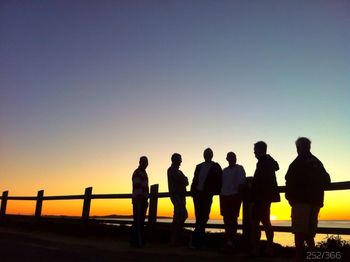 Silhouette of friends standing against clear sky at sunset